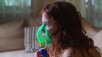Sick girl making inhalation with nebulizer to reduce coughing, at home, child taking medication while breathing in through face mask. Bronchitis and asthma treatments for children photo