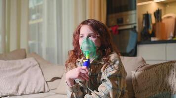Sick girl making inhalation with nebulizer to reduce coughing, at home, child taking medication while breathing in through face mask. Bronchitis and asthma treatments for children photo