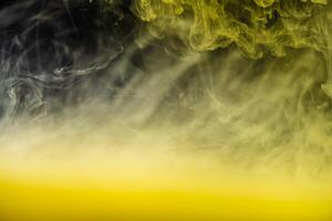 clouds of yellow smoke on a black background, clouds of paint in water, aquarium, abstract background, texture photo
