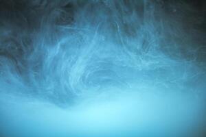 clouds of blue smoke on a black background, clouds of paint in water, aquarium, abstract background, texture photo