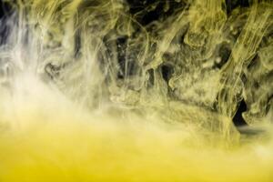 clouds of yellow smoke on a black background, clouds of paint in water, aquarium, abstract background, texture photo
