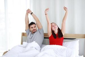 Smiling Caucasian lover Couple wake up and stretch lazily on the bed in the morning on holiday at home. Lifestyle and relationship of married life Concept. photo