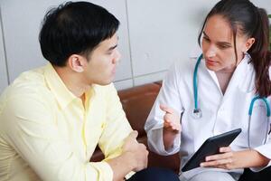 Professional Caucasian Female Psychiatrist is talking and counseling and researching on website with tablet for treatment young asian man. Major depressive disorder patients and healthcare Concept. photo