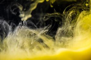 clouds of yellow smoke on a black background, clouds of paint in water, aquarium, abstract background, texture photo