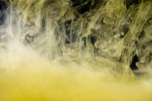 clouds of yellow smoke on a black background, clouds of paint in water, aquarium, abstract background, texture photo