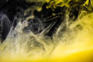 clouds of yellow smoke on a black background, clouds of paint in water, aquarium, abstract background, texture photo