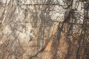 Background image of a cracked textured stone wall that has passed the test of time. photo