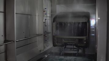 Robots at the factory paint the cab of the car. SCENE. At the factory, a white car is painted by robotic hands. On the assembly line, the car is painted in a light color. The car body is painted on video