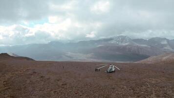 Top view of helicopter standing on mountain. Clip. Helicopter stopped on mountain with view of horizon with clouds. Beautiful landscape with mountains and sun rays in cloudy clouds video