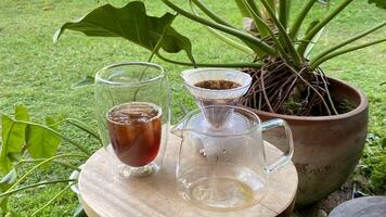 there is a pitcher and a glass of coffee on a table photo
