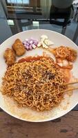 a plate of noodles with meat and vegetables on a table photo