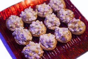 Tartlets or mini tarts with corn and crab salad on red plate photo