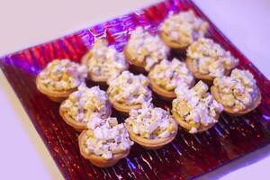 Tartlets or mini tarts with corn and crab salad on red plate photo