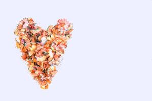 Wooden pencil shavings and colorful crumbs of graphite from sharpener in a shape of heart on white background. Top view. Design elements for poster, banner, cards photo