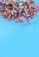 Wooden pencil shavings and colorful crumbs of graphite from sharpener on soft pastel paper background. Top view. Design elements for poster, banner, cards photo