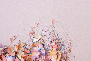 Wooden pencil shavings and colorful crumbs of graphite from sharpener on soft pink pastel paper background. Top view. Design elements for poster, banner, cards photo