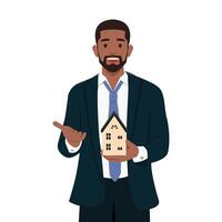 Young bearded business man holding home model and presenting with hand and pointing with finger. vector