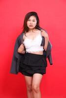 studio portrait of an elegant young indonesia woman on the left side wearing a white tank top covered in a formal gray jacket while holding it. for personal concepts, branding and advertising photo