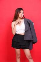 candid studio portrait of a young, elegant Asian woman wearing a white tank top covered in a formal gray jacket with her arms around her chest. for personal concepts, branding and advertising photo