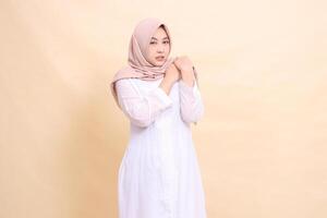 girl asian wearing a white hijab dress stands in pain with both hands holding her shoulders shoulder pain. for health, care, education and science concepts photo