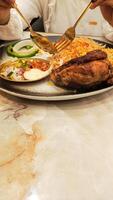 portrait of asian woman's hand about to eat a dish with a spoon and fork on a plate of nasi kebuli nasi kebuli typical arabic food photo