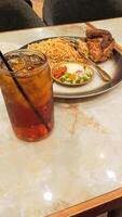 portrait of kebuli rice nasi kebuli and iced tea, typical Arabic food made in Indonesia on a table with empty space beside it at a 45 degree angle photo
