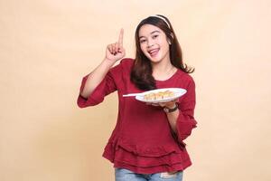 beautiful young asian woman in red happy carrying a plate of dimsum chinese food and chopsticks while pointing up. used for food, health and lifestyle content photo