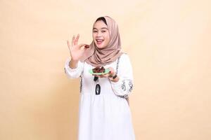 a beautiful indonesia Muslim woman wearing a hijab with a cheerful smile took a date forward and brought some dates for sahur and breaking the fast. used for advertising, health, Eid and Ramadan photo