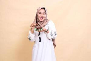 a beautiful indonesia Muslim girl wearing a happy hijab took a date and brought some dates for the sahur menu and breaking the fast. used for advertising, health, Eid and Ramadan photo