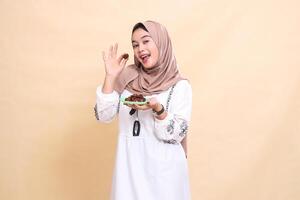 a beautiful indonesia Muslim woman wearing a hijab with a cheerful smile took a date and brought some dates for sahur and breaking the fast. used for advertising, health, Eid and Ramadan photo