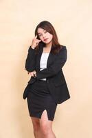Beautiful Asian executive young woman standing elegantly and looking at camera pose holding hair in arms, quarter body portrait on yellow background for commercial, corporate and business photo