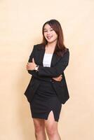 Beautiful young indonesia executive woman standing right side up cheerful and looking at camera pose with arms crossed, half body portrait on yellow background for commercial, corporate and business photo