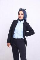 young indonesia office girl in blue shirt hijab standing to the camera elegantly straight arms down and waist. Beautiful Muslim women use business, finance and fashion content photo