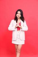 Portrait of a young Asian Indonesian woman smiling welcome wearing a cream-colored blazer. Isolated red background for content materials, banners, advertising. photo