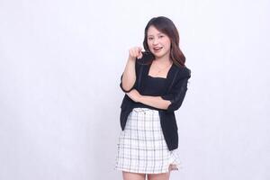 Beautiful Asian Indonesian girl in her 20s in the office surprised with arms crossed and pointing at the camera isolated on a white background photo