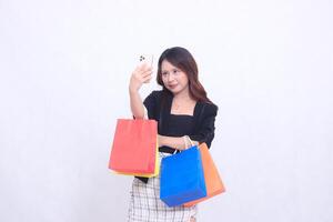 beautiful asian woman customer 20s formal office smiling while looking at cellphone with arms crossed while carrying shopping paper bag isolated white background photo