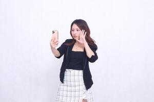 Beautiful Indonesian office woman in her 20s flat expression looking at her cream colored cellphone gadget while making a call for a promo isolated on a white background photo