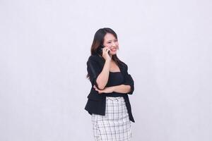 the charm of a beautiful Asian office woman in her 20s with a suspicious smile while making a phone call on a cell phone with her arms crossed isolated on a white background photo