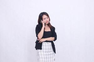 the charm of a beautiful Asian office woman in her 20s with a sad expression while making a phone call on a cellphone gadget with her arms crossed isolated on a white background photo