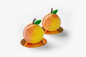 Two peach-shaped pastries dusted with sugar on golden cardboards photo