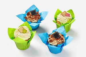 Vanilla and chocolate cupcakes with whipped cream in paper wrappers photo