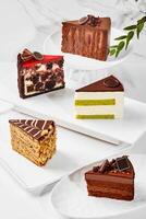 Slices of various cakes arranged on plates on marble surface photo