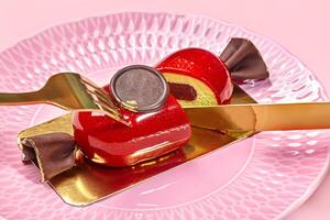 oro cuchillería rebanar en forma de caramelo mousse postre en rosado plato foto