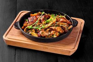 Roasted pork chuck with mushrooms, potatoes, onions and greens in frying pan photo