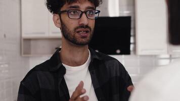 Young curly man in glasses shouting at a young woman and gesticulating in the kitchen at home during a quarrel close up. Concept of problems in the relationship of a couple video