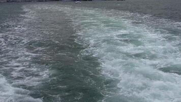 A boat sails on the open ocean, leaving a wake under the blue sky and on the tranquil waters video