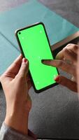 A person is using a smartphone with a green screen for a mockup in an office setting video