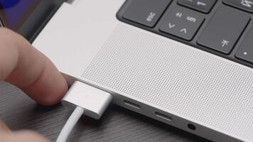 Insert the cable into the laptop. ACTION. Black keyboard in a silver laptop. Corner with buttons on the keyboard of a silver laptop with a white wire video