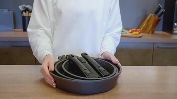 The woman moved the handle of the frying pan into a pile of other frying pans. ACTION. The cook holds a frying pan handle in his hand. Black frying pan in the hands of the cook. The cook took all the video