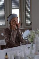 mujer limpieza piel con micelar agua y algodón almohadilla y mira en el espejo foto